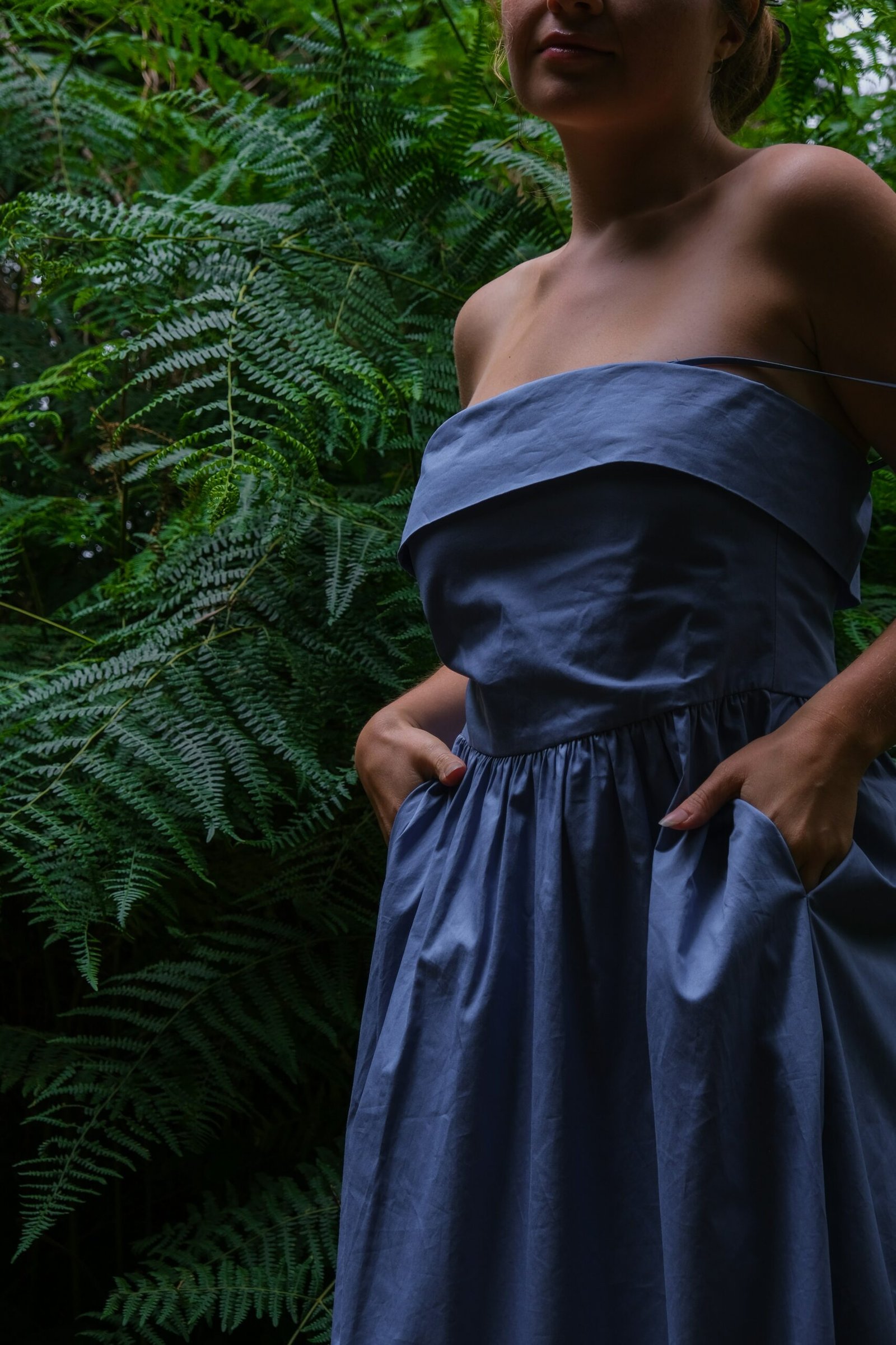 a woman in a blue dress standing in a forest